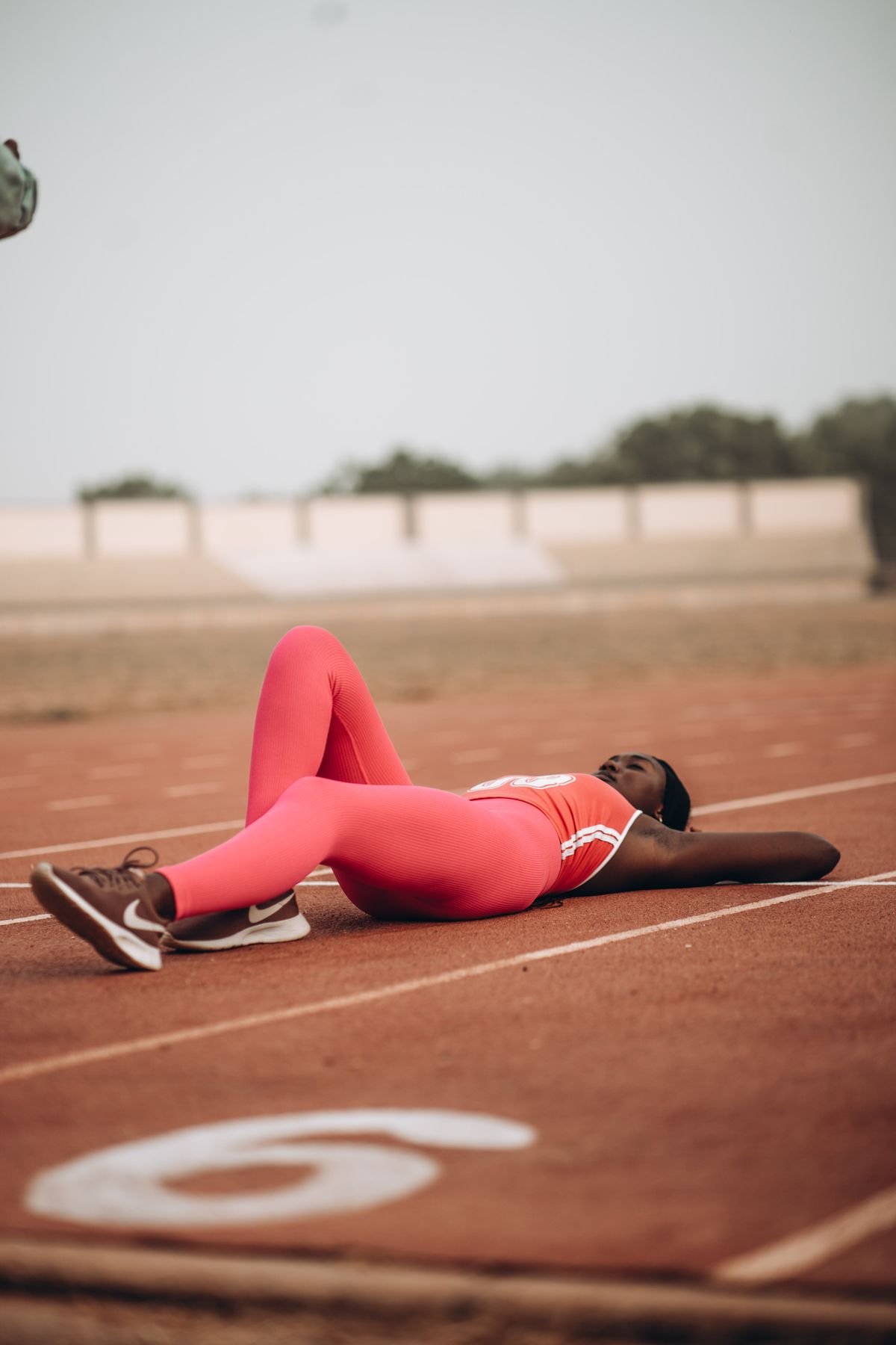 A tired runner resting on the track after a race — a visual representation of accumulated fatigue and the need for a deload week